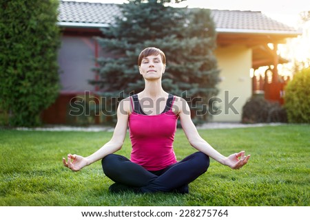 Young fit woman in sportswear practice yoga outdoor, closed eyes