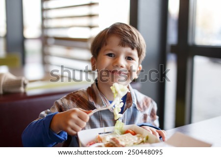 Little child eating salad in fast food restaurant