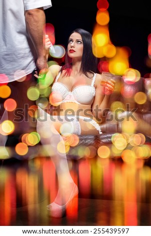 Sexy couple behind glass, sensual woman in underwear pulling mans tie, seduction, with night bokeh lights