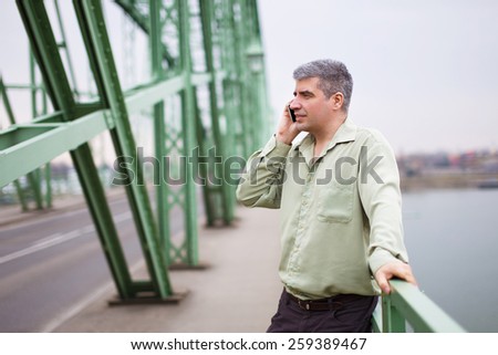 Young businessman calling at green bridge, successful entrepreneur