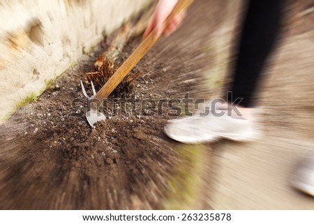 Woman hoeing soil outdoor, works at spring