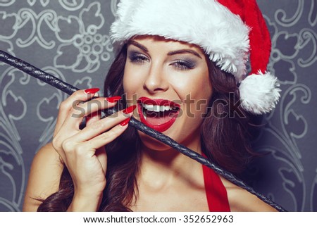 Sexy santa woman with whip, vintage style, red lips and nails, bdsm