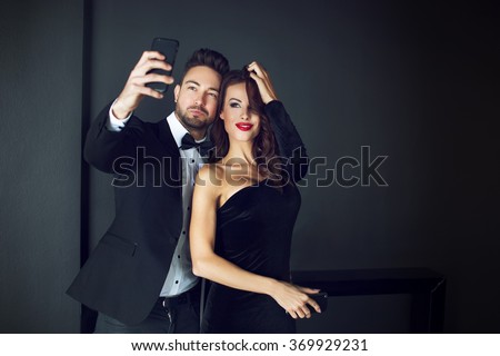 Fashionable rich celebrity couple taking selfie indoor