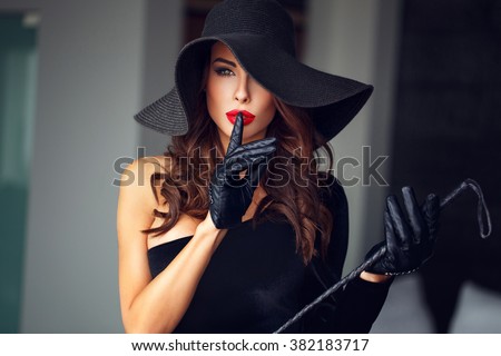 Sexy dominant woman in hat and whip showing no talk, bdsm
