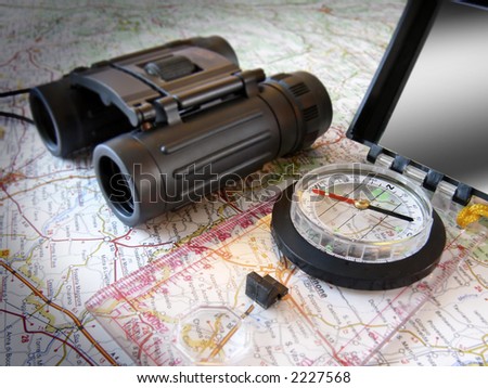 still life: hiking compass and binoculars on map (of Italy - but only occasional place name legible); differential focus