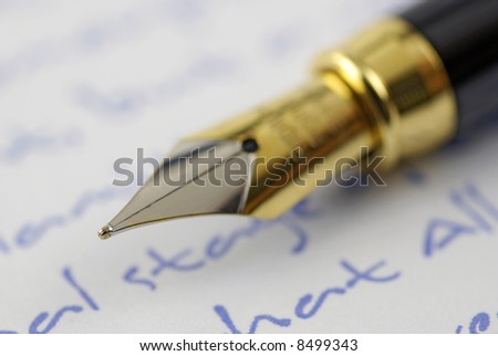 gold fountain pen nip resting on written background; differential focus