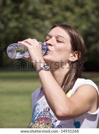 happy, beautiful young woman drinking from a bottle of spring water