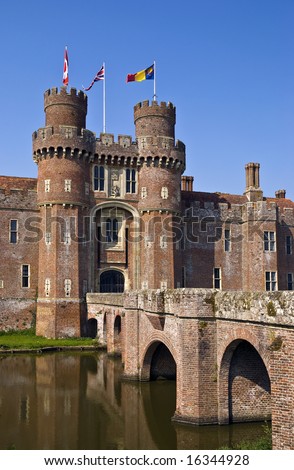 15th century English moated castle flying flags of Canada and the United Kingdom (union flag); reflection in the moat
