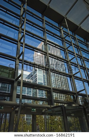 towering office blocks seen through glass atrium, London Docklands, against clear blue sky