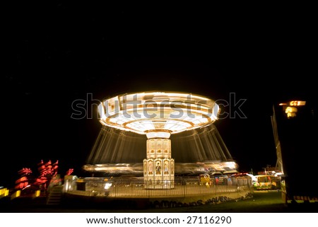 brightly-lit chair-o-plane fairground ride, against a pure black sky