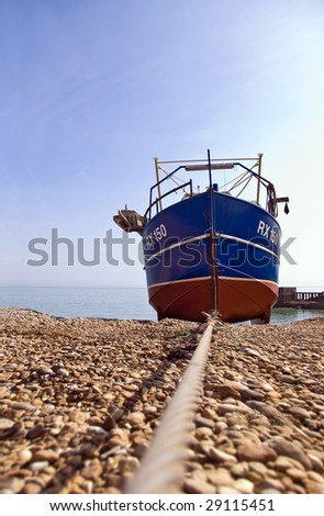 traditional trawler fishing boat drawn on to beach with steel hawser; differential focus, very pronounced perspective