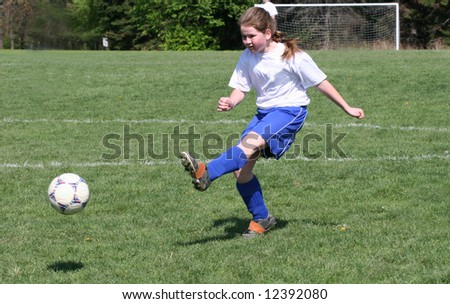 Teen Youth Girl kicking ball in air at soccer game.