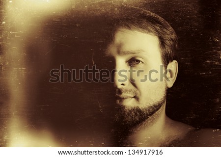 vintage-like low key portrait of young man with beard and hairy shoulders