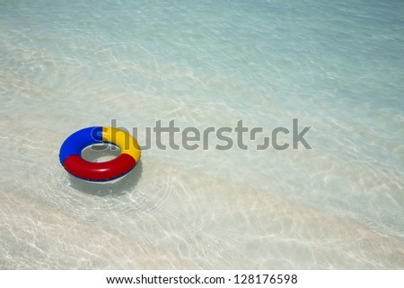 red, yellow and blue plastic swimming ring floating in a turquoise sea