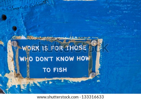 blue sign on a fishing boat with the worldly wisdom: Work is for those, who do not know how to fish