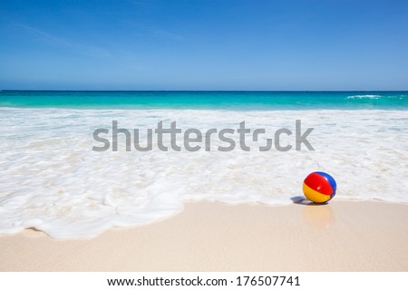 travel background with a colorful water ball at the beach and a turquoise sea and a blue sky in the background