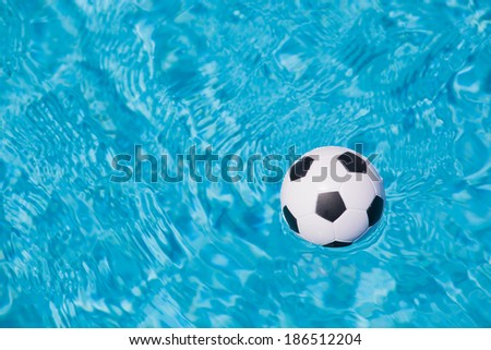 sport background of a little plastic football floating in the blue water of a swimming pool