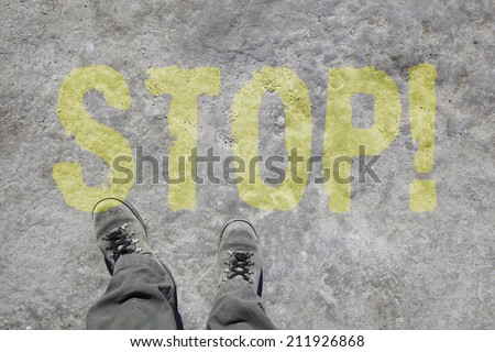 man in grey military boots and pants is looking down to his feet. On the stony ground is written time to go in yellow color.