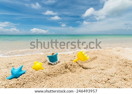 travel background with yellow and blue plastic toys in the sand of a beautiful beach, Le Morne, Maurtius, Africa
