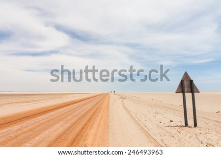 background of a red sandy desert road in the Namib and the backside of a warning triangle road sign, Skeleton coast National Park, Namibia, Africa