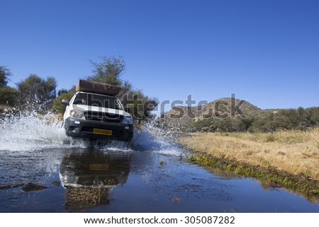 white four by four car crossing a river with splashing water, Travel concept for off-road adventure and fun in a south  african landscape
