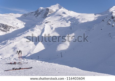 Two pairs of skis, ski lifts and pistes and Hintertux Glacier in Zillertal Alps in Austria at sunset light