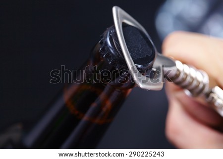 A hand opening a bottle of beer