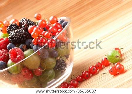 Fruit mix in the glass container, on a table from straw