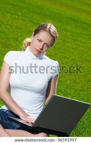 The girl with laptop on a green lawn
