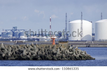 Sea port with storage tanks in background. Concrete pier in focus in foreground