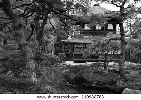 Black and white picture of temple hidden in japanese garden