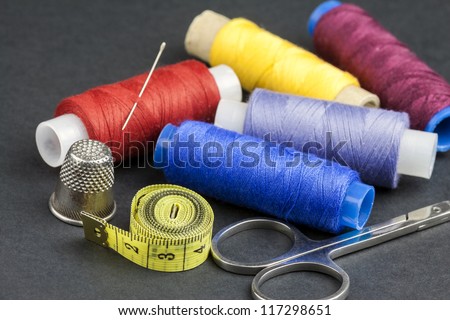 Tailors tools - scissors, spools of thread, measure, needle and thimble - isolated on black background
