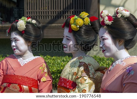 KYOTO, JAPAN - MARCH 27, 2012: Three Japanese women in traditional kimono smiling and pose to tourists on the street of Kyoto, Japan.