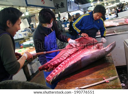 TOKYO, JAPAN-APRIL 5, 2012: Three workers slicing tuna in Tokyo Tsukiji fish market, Japan