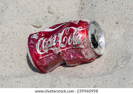 VILNIUS, LITHUANIA - JULY 28, 2014: Photo of empty and crushed Coca-Cola can lying on the beach sand.