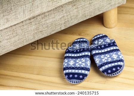 A pair of wool slippers standing by couch in living room