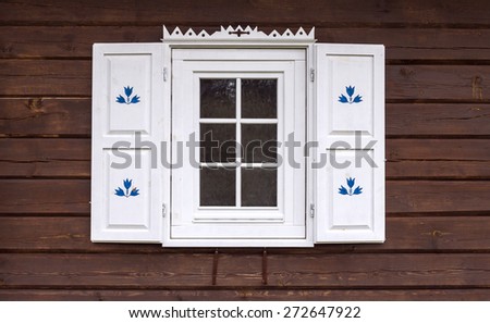 Facade of the old traditional log house with white decorated window