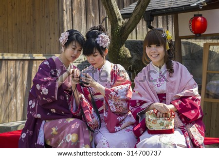 KYOTO, JAPAN - MARCH 27, 2012: Three modern japanese girls wearing traditional kimono and enjoying warm day near Kiyomizudera Buddhist temple in Kyoto, Japan.
