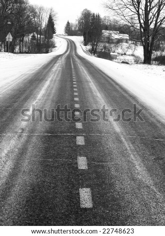 Black and white picture of the country road in winter, focus on dividing line