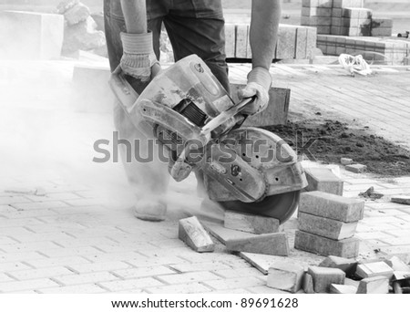 Black and white picture of worker with concrete saw in his hands and working