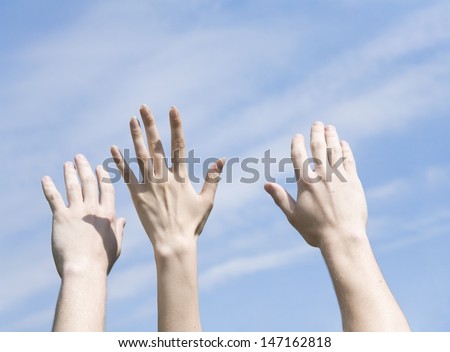 hands are lifted to a blue cloudy sky