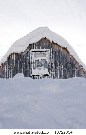 roof and window of a wooden small house covered with snow in the cold winter afternoon