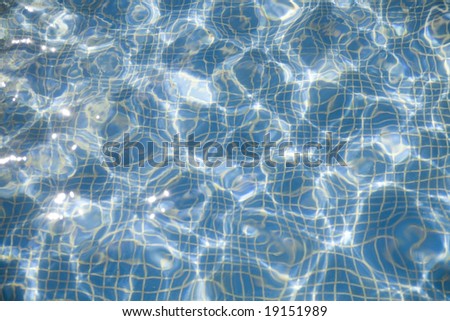 Pure blue transparent water with patches of light from the sun in pool