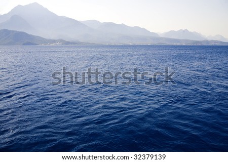 blue waves of Mediterranean on a background mountains and sky
