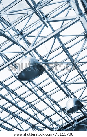 blue toned lamps and metallic girders under glass ceiling of industrial building