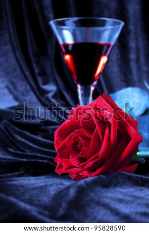 Gentle red rose and liquor in a glass on a dark blue background