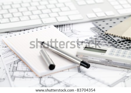 Ruler calculator, metric folding ruler, notepad, pen and architectural drawings of the modern house