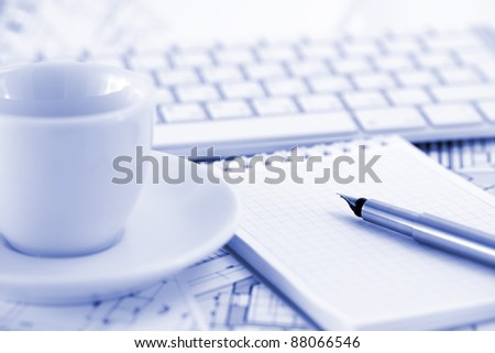 keyboard, white cup, notepad, pen ,and architectural drawings