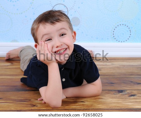 sweet boy posing with a silly grin and hand on chin. laying on floor