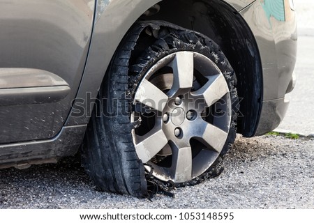 Destroyed blown out tire with exploded, shredded and damaged rubber on a modern suv automobile. Flat low profile tyre on an alloy rim, ripped open in pieces with visible interior.